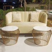 Beige sofa with white cushions and two gold wire side tables on a patio at night.
