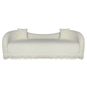 A beige velvet loveseat sofa with a beige fringe trim along the bottom front.