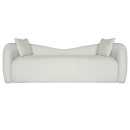 A modern curved beige velvet sofa with two matching square throw pillows, shown from a front-facing perspective