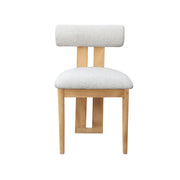 A modern wooden dining chair with a textured, light gray bouclé seat and backrest cushion, set against a plain white background.