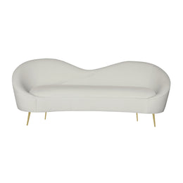 A modern curved chaise lounge chair upholstered in beige velvet with slim gold metal legs.
