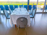 Dining table set for four with a view of a green field through large windows.