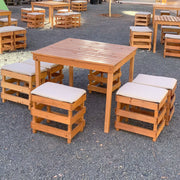 Wooden outdoor furniture set with tables and stools on a gravel surface