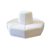 A modern white upholstered modular seating unit with a central pedestal backrest and a low hexagonal base, shown on a plain white background.