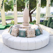 Round white outdoor sofa with patterned cushions in a garden setting.
