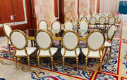 Gold and white chairs arranged around a large dining table in a formal setting.