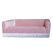 Pink sofa with white fringe trim on a white background