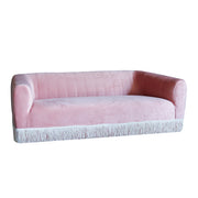 Pink sofa with fringe trim on a white background